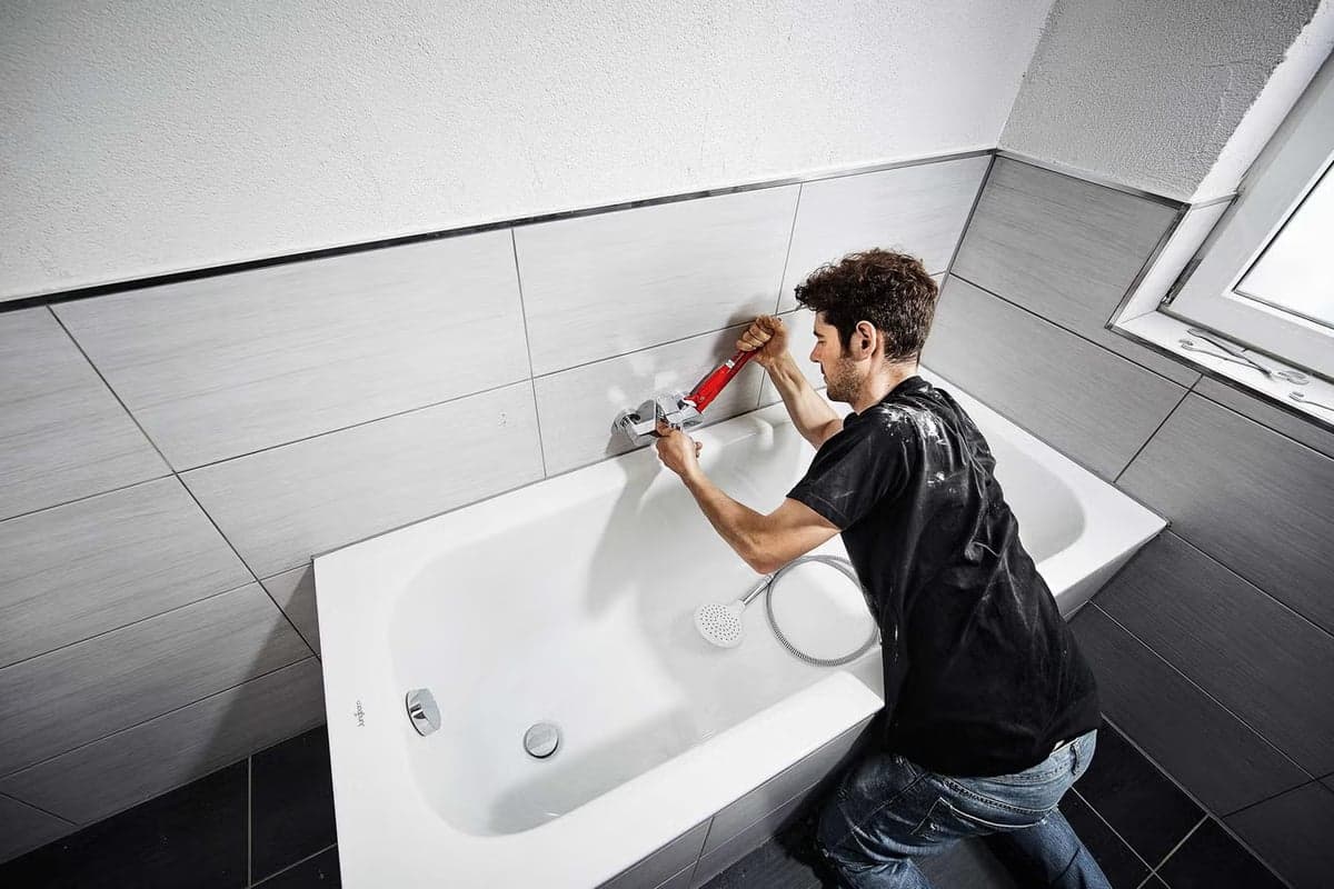 Loodgieter installeert bad en badkraan in nieuwe badkamer